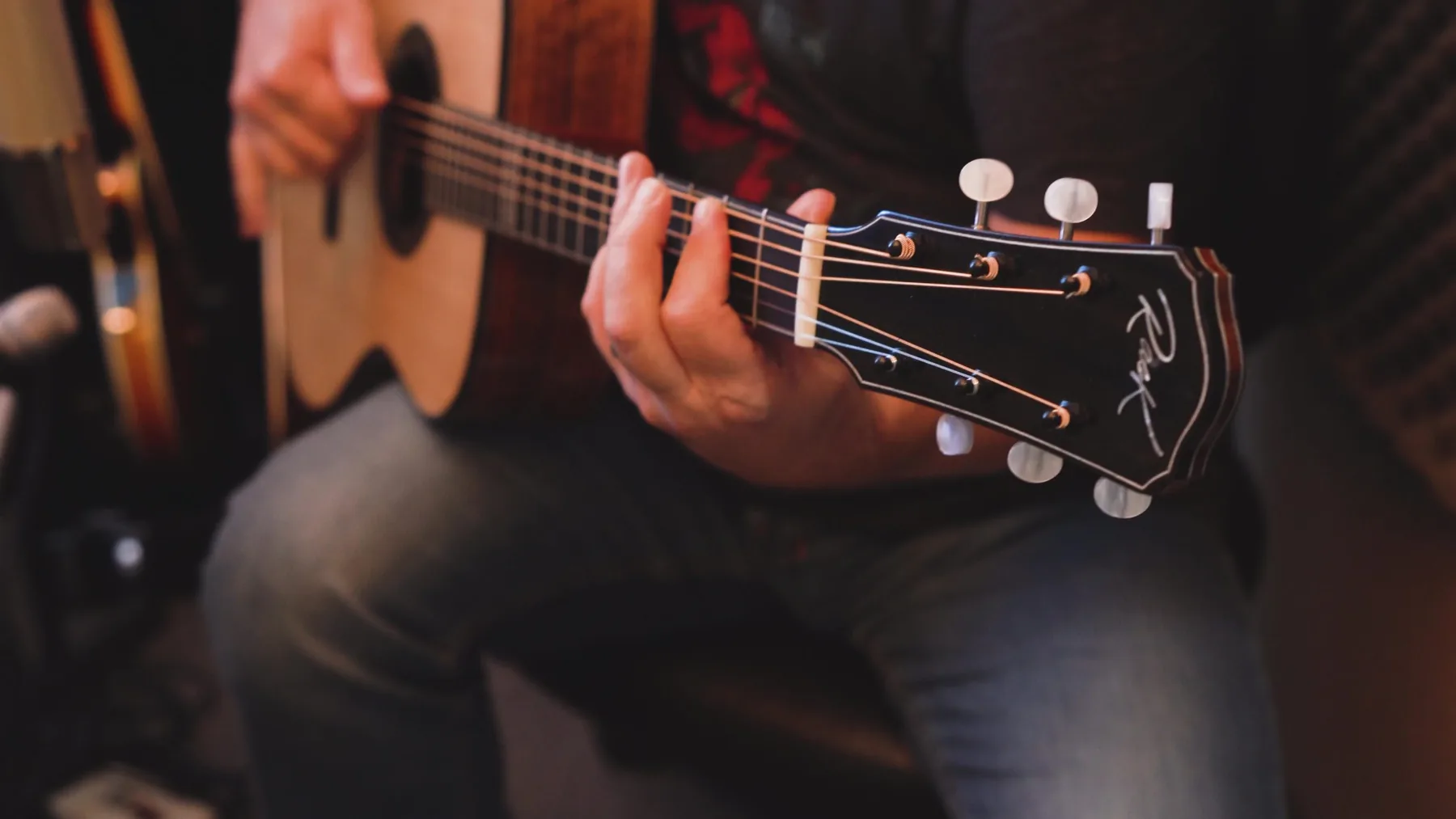 A musician playing a Rask acoustic guitar