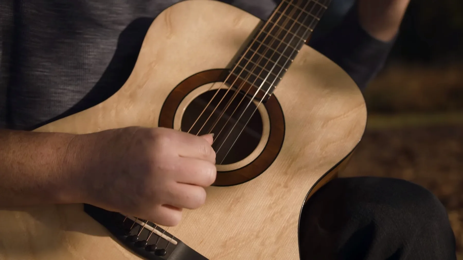 Close-up of a musician playing a natural-finish acoustic guitar